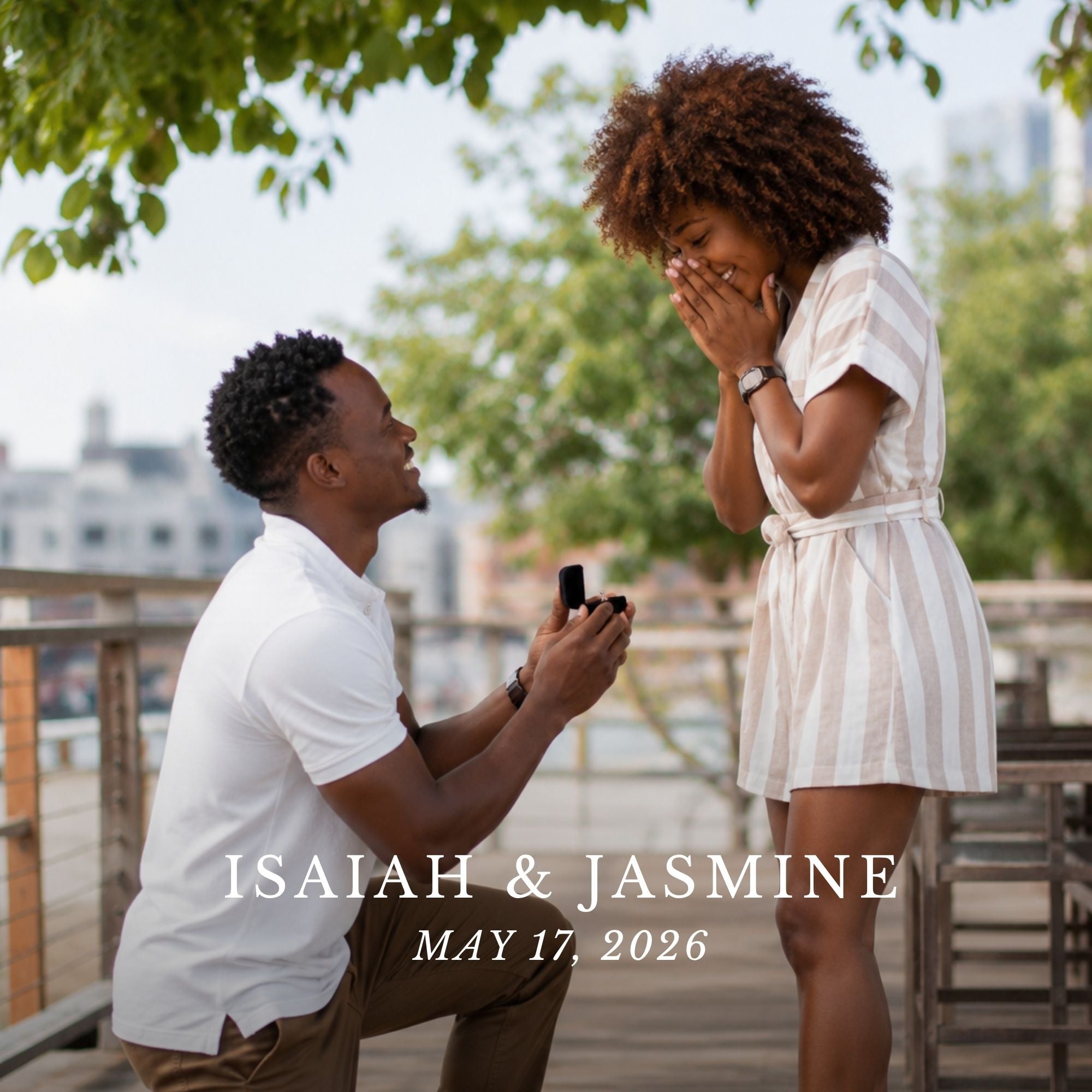 A man kneels on a wooden deck outdoors, holding an open ring box while looking at a woman standing and covering her face with her hands. The scene is framed with green tree leaves at the top and includes overlaid text reading 'ISAIAH & JASMINE' and 'MAY 17, 2026'.