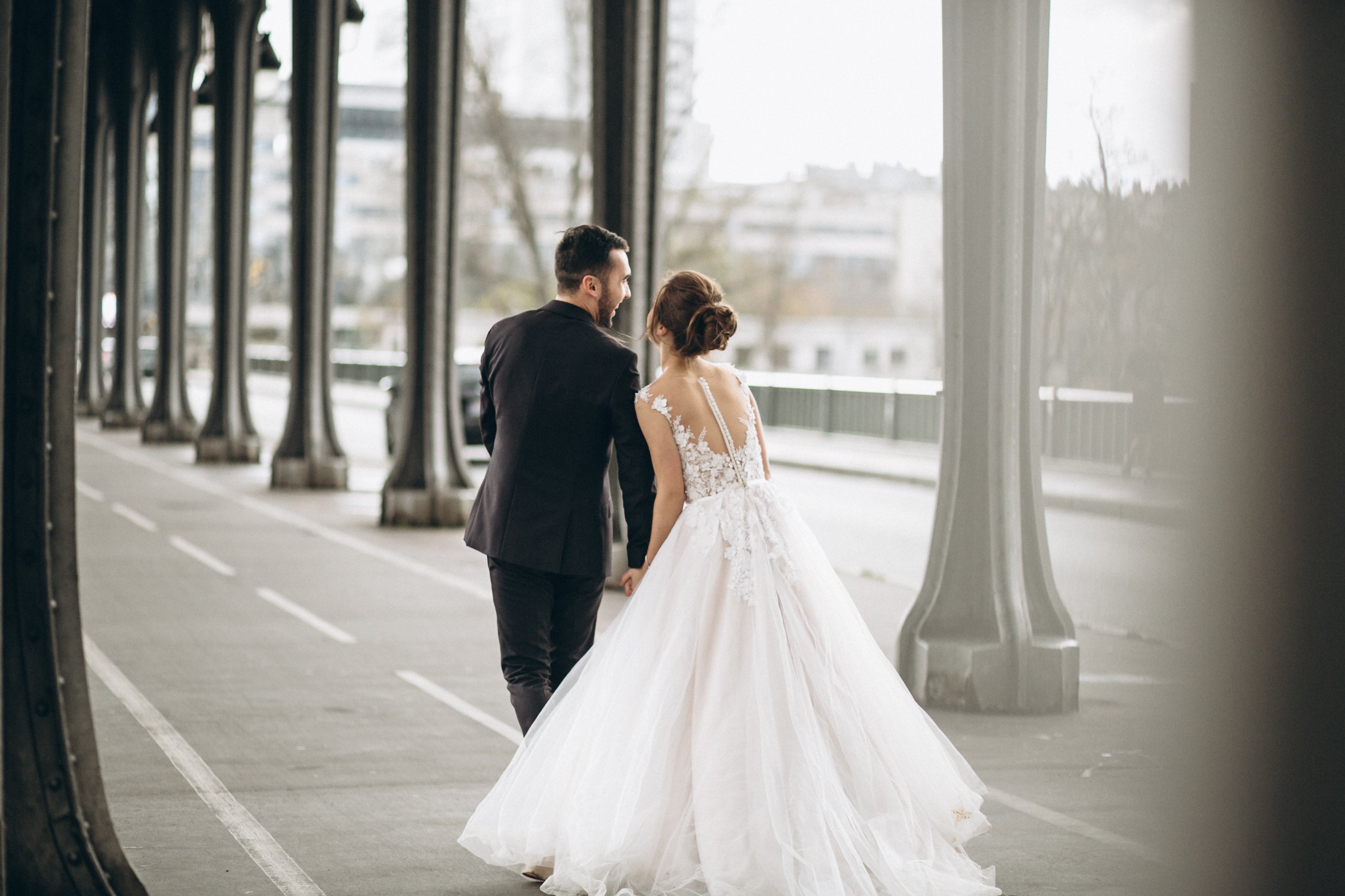 Man and woman in wedding attire standing on a bridge