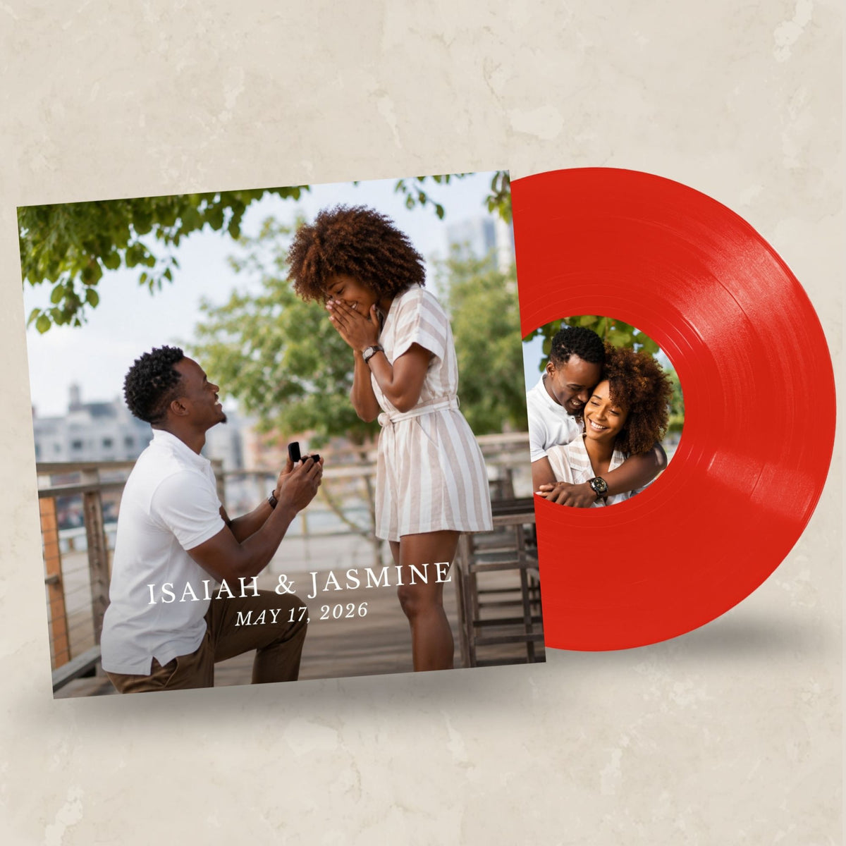 A custom vinyl record album cover and red vinyl disc shown on a textured beige background. The album cover features a photo of a man proposing to a woman on a balcony, with the text 'ISAAH & JASMINE' and 'MAY 17, 2026'.