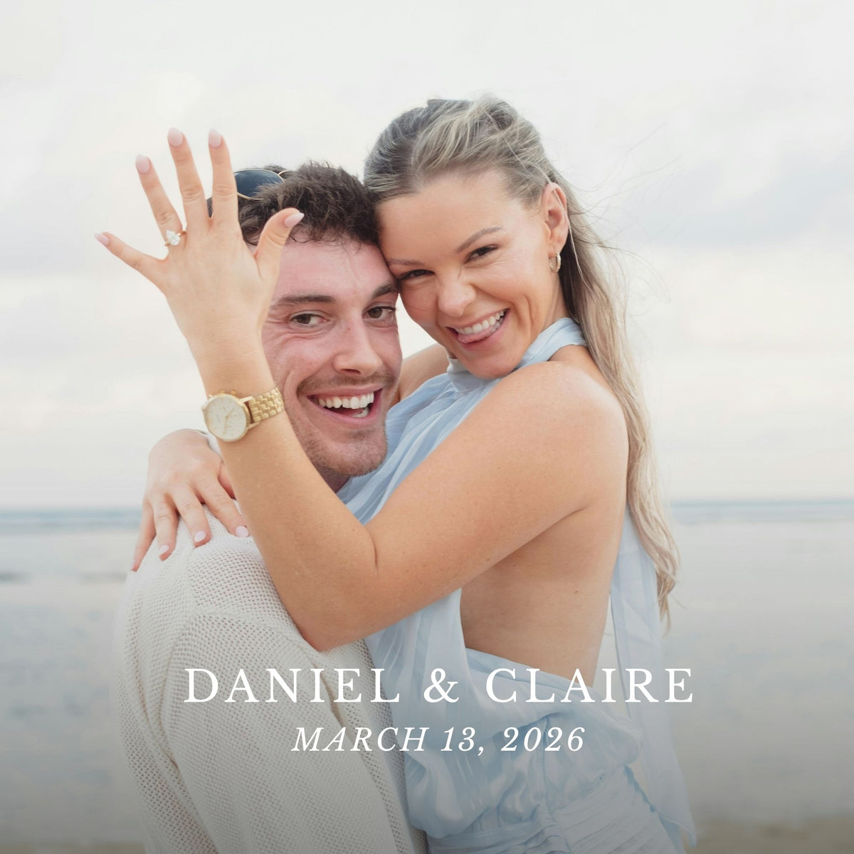 A smiling couple embracing on a beach, with the woman showing off a gold wedding band on her finger. The text overlay reads 'DANIEL & CLAIRE' and 'MARCH 13, 2026'.