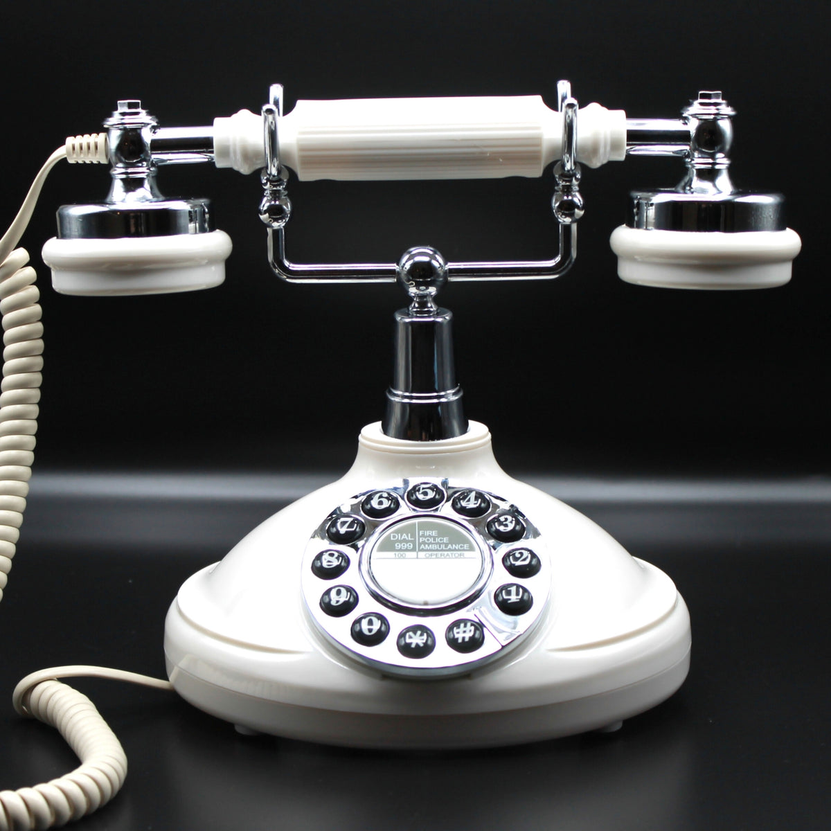 A vintage-style rotary telephone with an off-white/cream plastic body and handset, accented by shiny chrome metal parts and black button details, set against a solid black background.